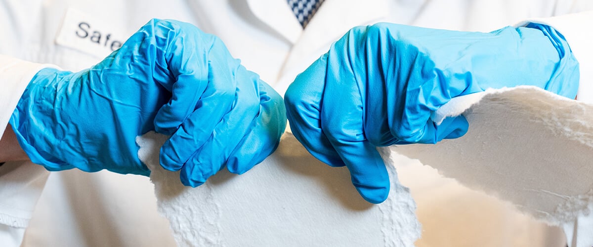 Hands in blue gloves rips paper apart