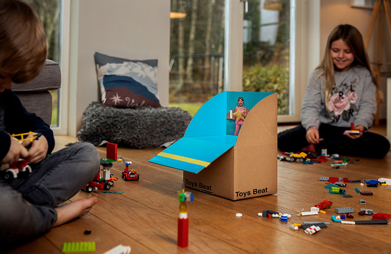 Children playing indoors with toys, Lego and a box