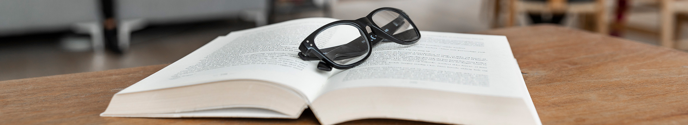 Reading glasses and open book on table