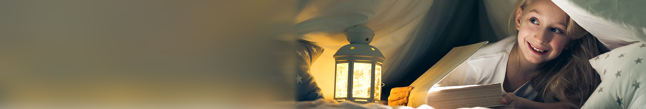 Young girl reading under sheets