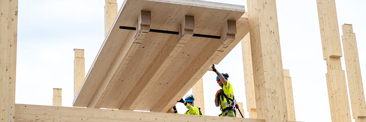 Two construction workers lifting a CLT element at ByggPartner's new head office in Borlänge, Sweden.