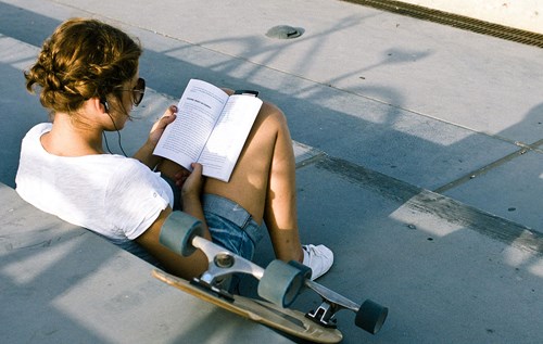 Young woman reading a paperback book on steps